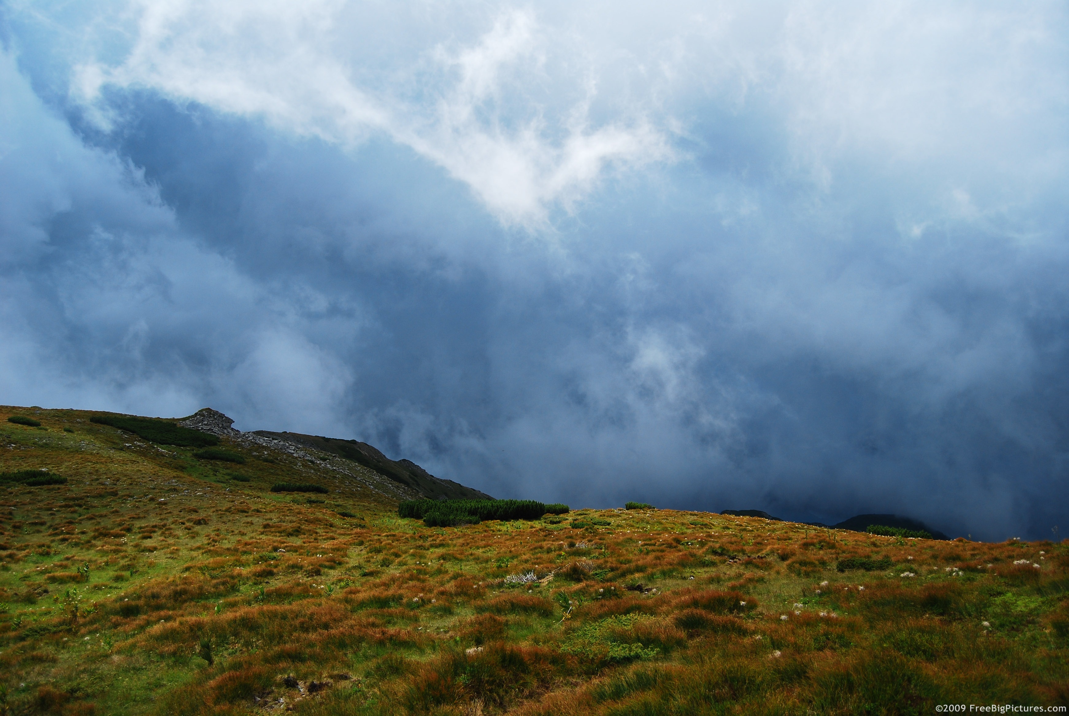 Stormy clouds on the sky over a mountain ridge covered with grass
