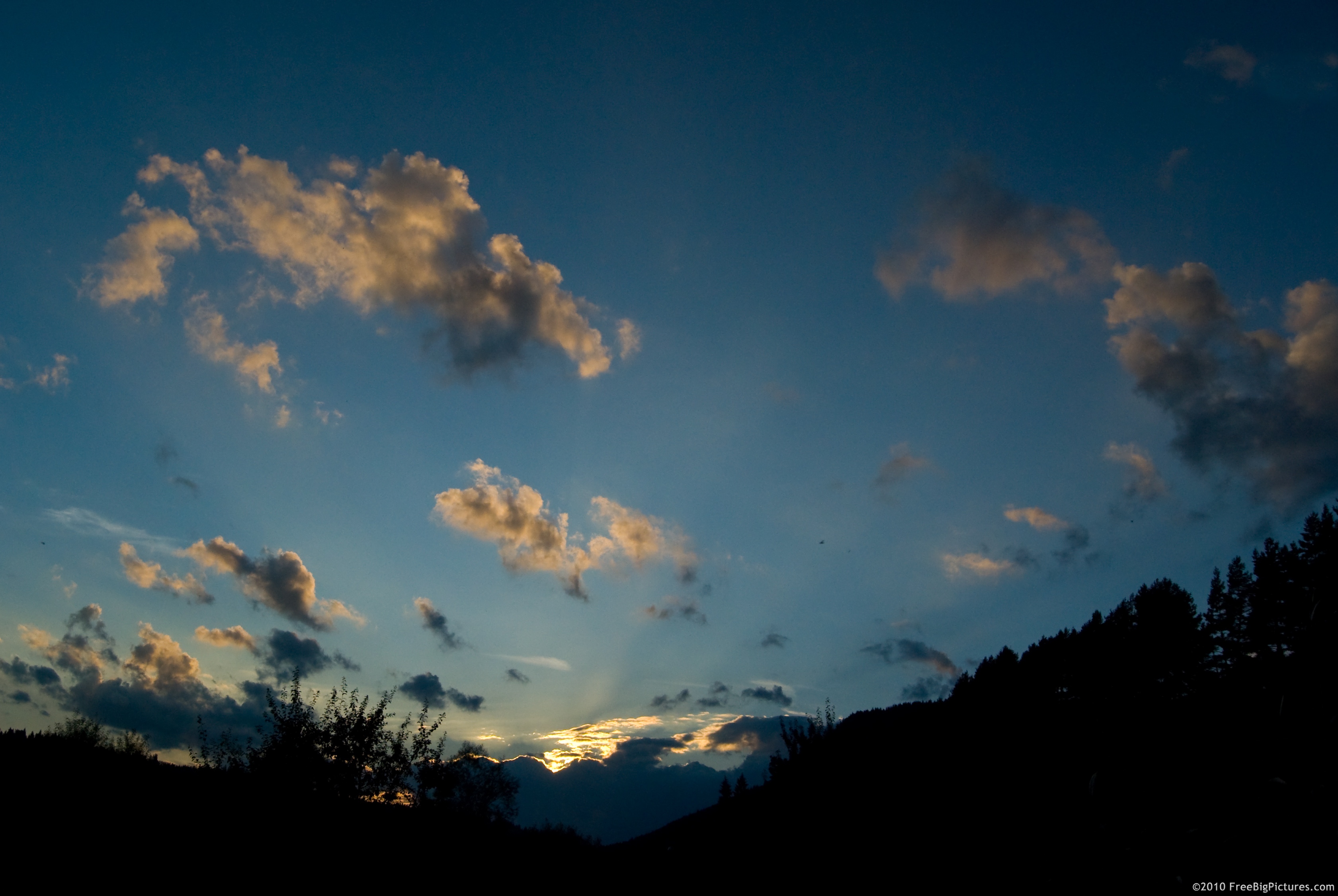 Fragments of clouds with golden hues on a blue sky at twilight
