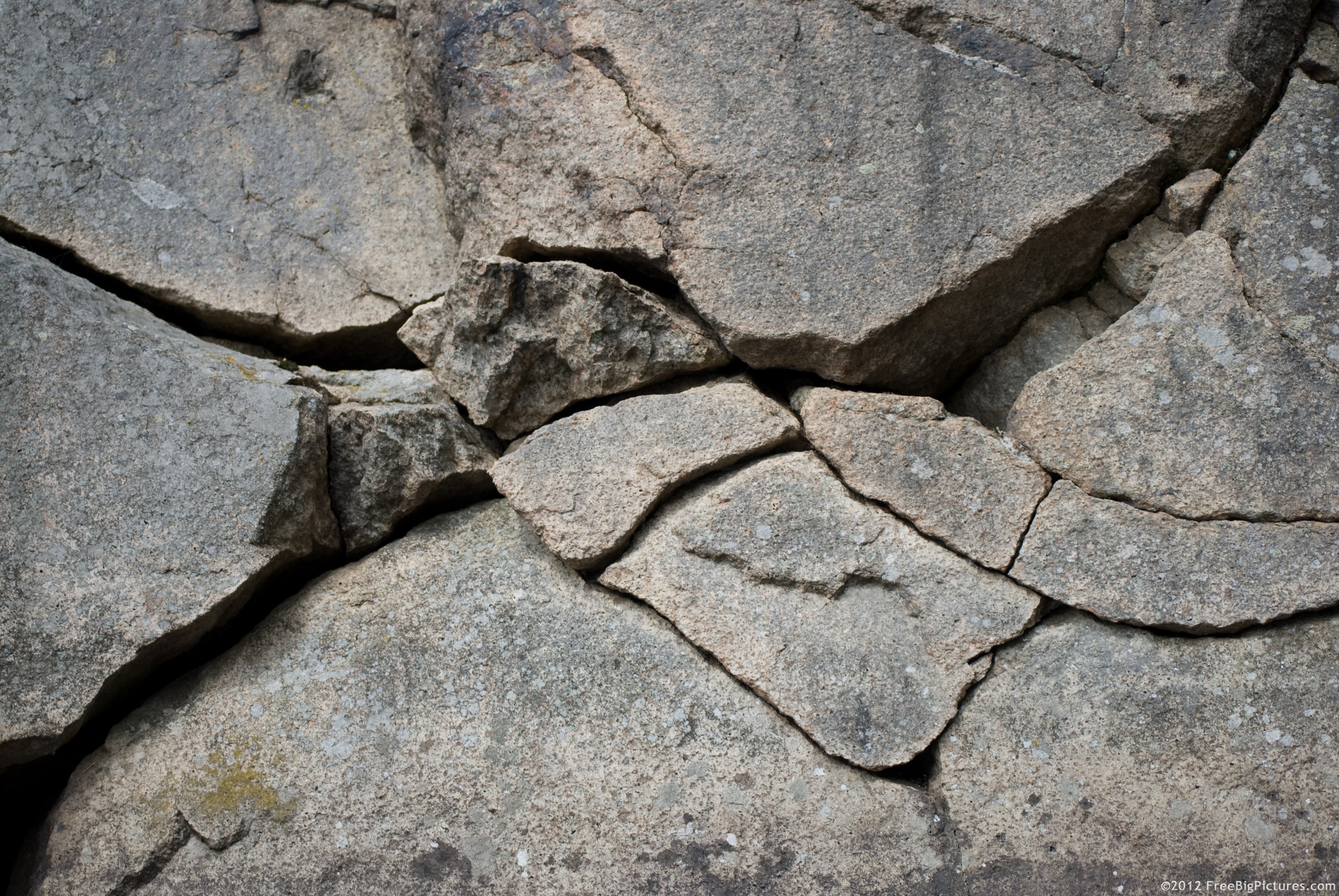 A basalt cracked stone wall with deep, black crevices